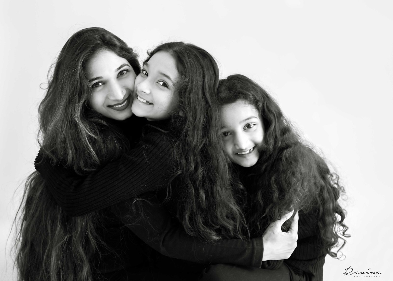Mother and two daughters hugging in a black and white family portrait by Ravina Photography, Seattle