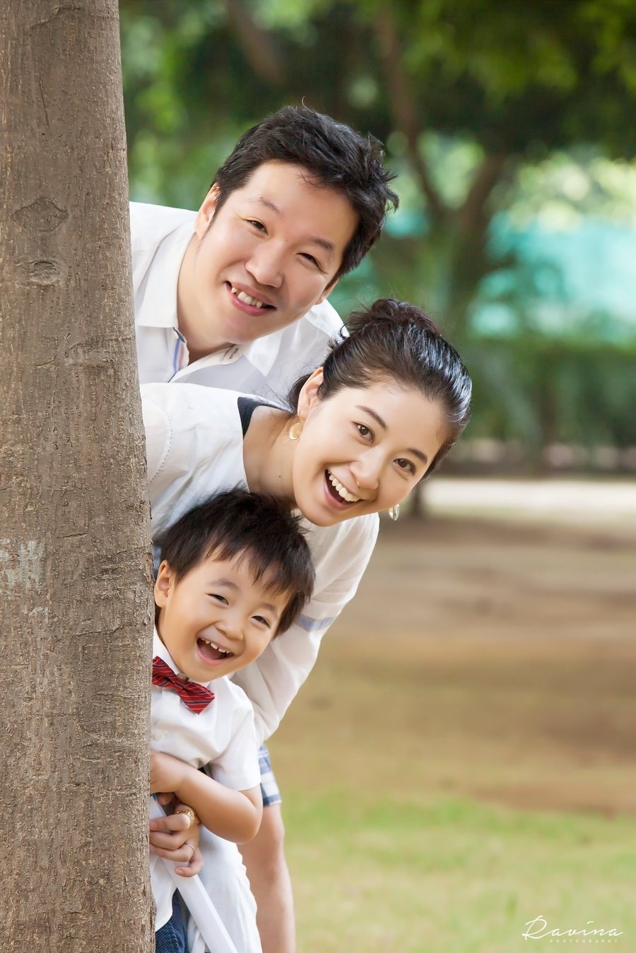 Family peeking out from behind a tree and laughing, Seattle family photography by Ravina Photography