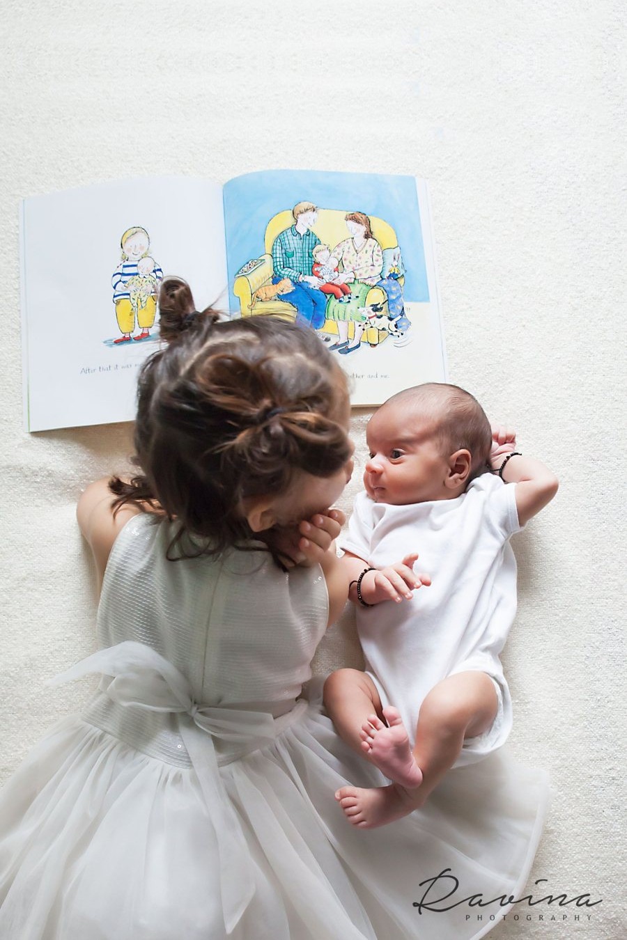 Big sister gazing at her newborn sibling, Seattle newborn photography by Ravina Photography